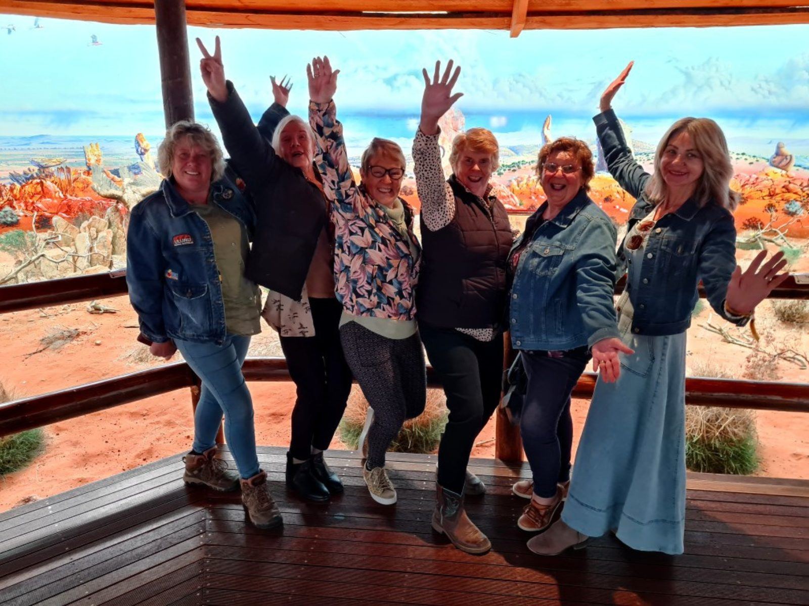 A group of women celebrating with arms raised on a deck