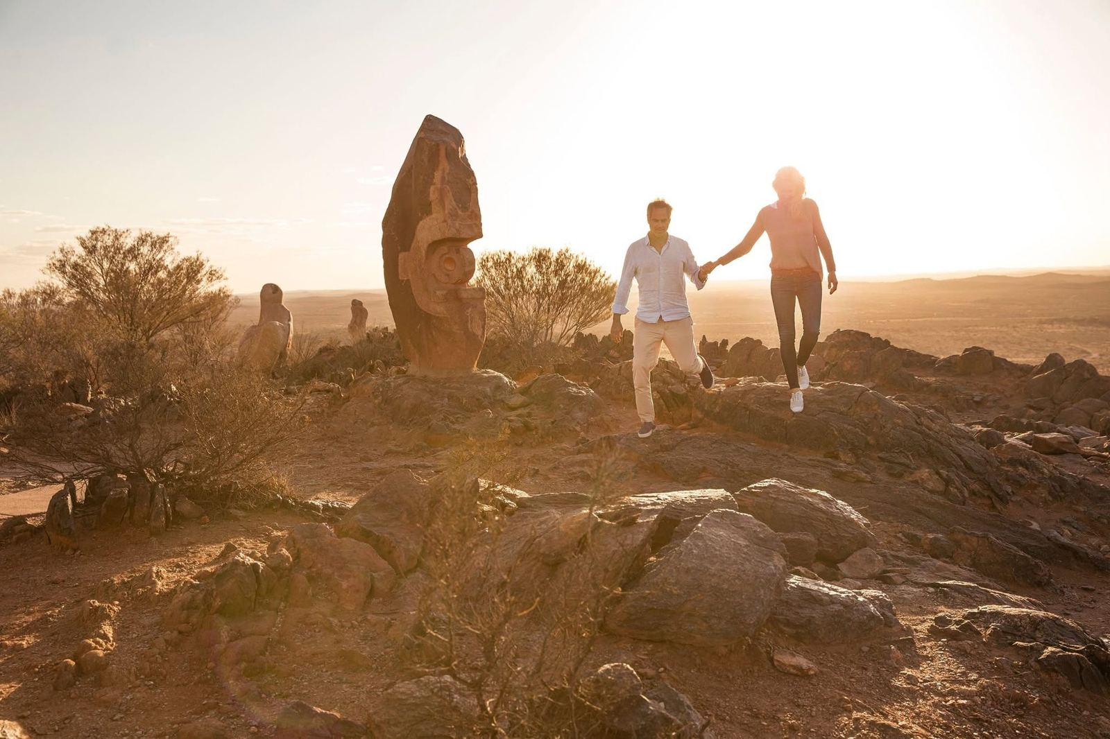 A couple walking hand in hand at the Living Desert Sculptures in golden sunset light